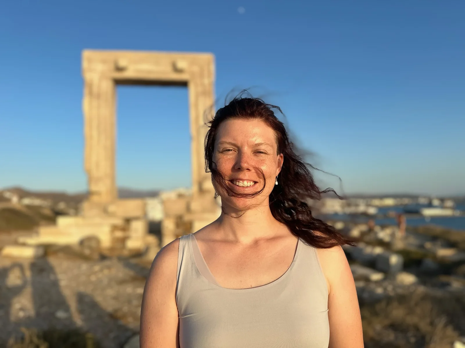 Harleigh Yarbro smiling at golden hour, with the Portara of Naxos behind her